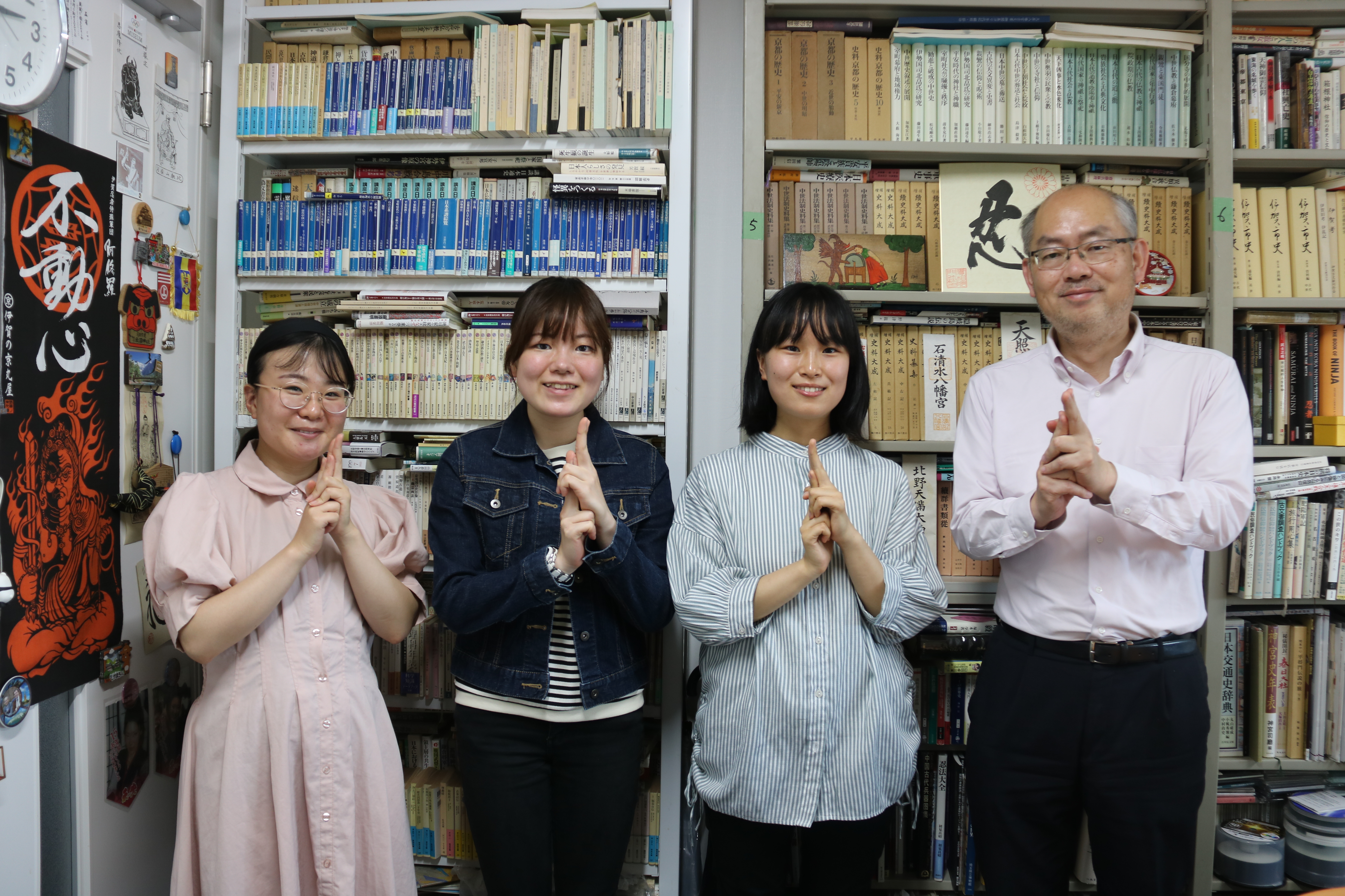 山田教授と３人の学生が胸の前で印を結び忍者のポーズをしている