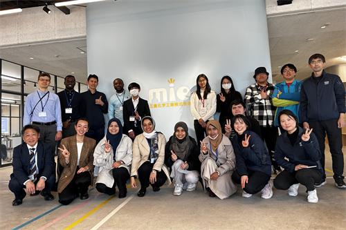企業ロゴを背景にした集合写真