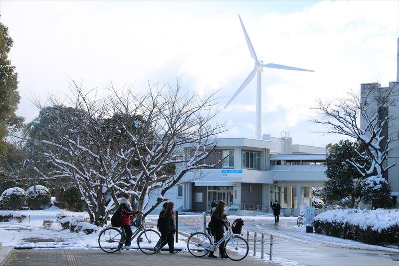 雪の中キャンパスを歩く学生