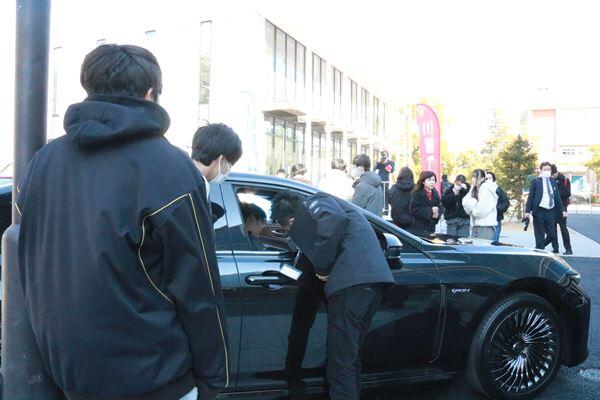 学生が電気自動車の運転座席に座る様子