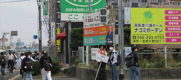 信号を守りましょう！という看板を持って指導する様子